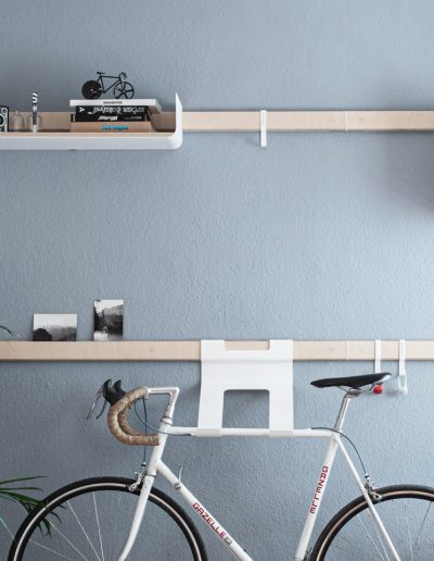 Variand Regalsystem vor blauer Wand mit Fahrradhalterung und Regalen